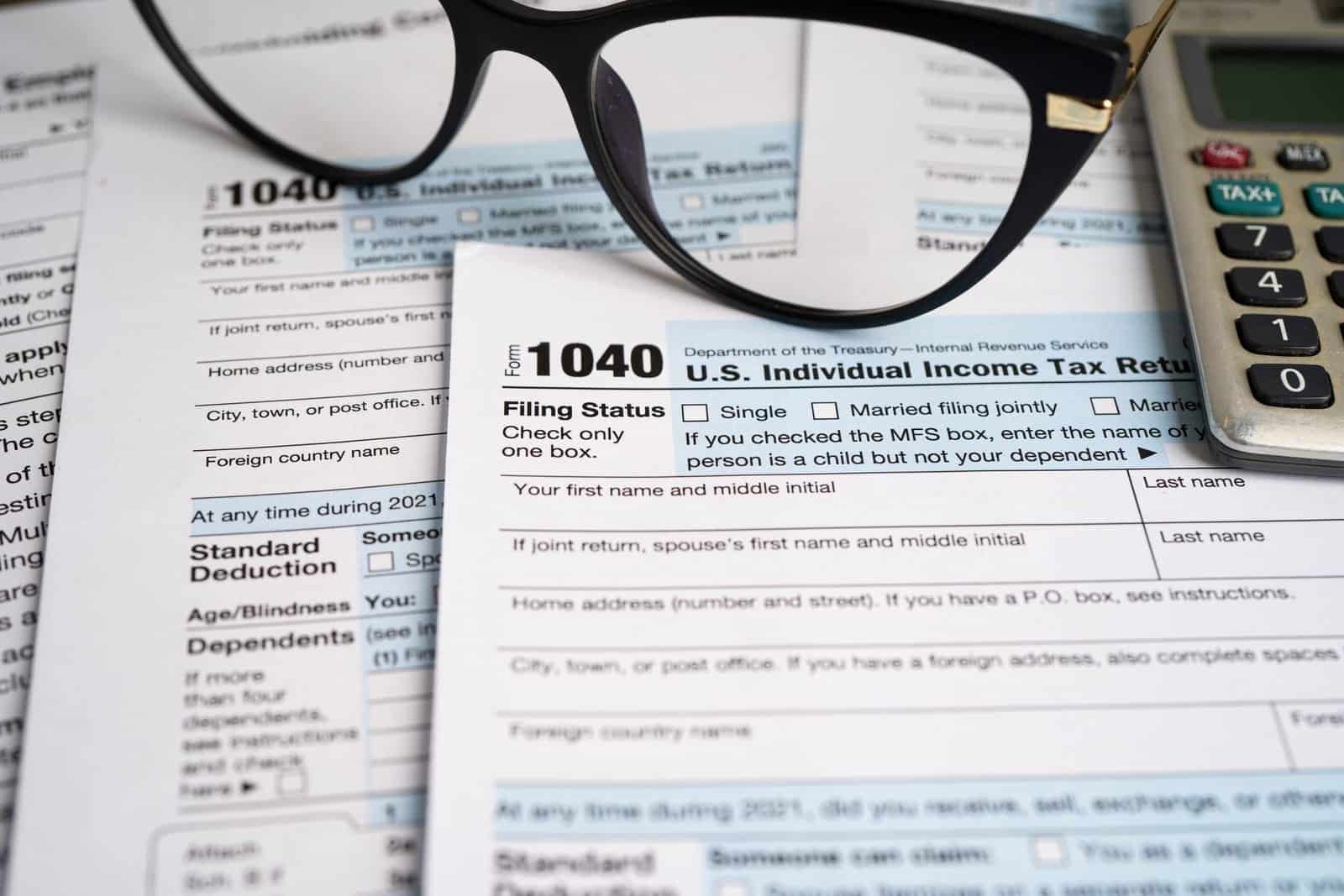 Form 1040 US Individual Tax Return Form with glasses and calculator